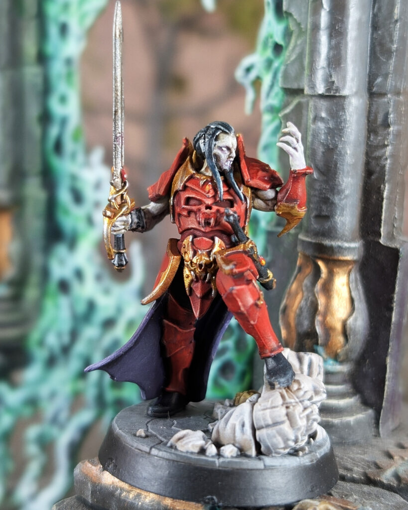 Finished Prince Duvalle miniature painted in a Blood Dragon-inspired color scheme with red armor, gold trim, purple cloak, and scenic base